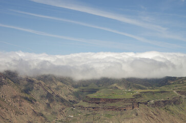 Aircraft vapor trails, sea of clouds and Mesa de Acusa. The Nublo Rural Park. Artenara. Gran Canaria. Canary Islands. Spain.