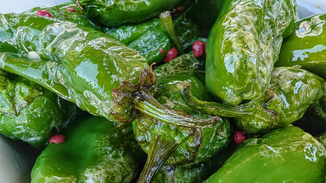 Close up of typical rustic spanish plate Pimientos de padron. Yammy green grilled pepers with spices, starter tapas. Vegan organic light summer meal