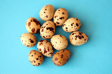 Few amount of quail eggs in small pile on blue background