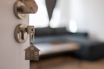 Open door to a new home with key and home shaped keychain. Mortgage, investment, real estate,...
