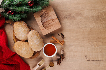 Homemade Christmas cookies in the shape of a cedar cone with ingredients: honey, sugar, spices on a wooden background with a branch of a Christmas tree with a copy of the space.