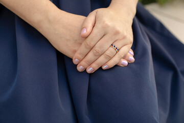 part of a female body, female hands with a ring on an elegant blue skirt, female hands aged 40-45...