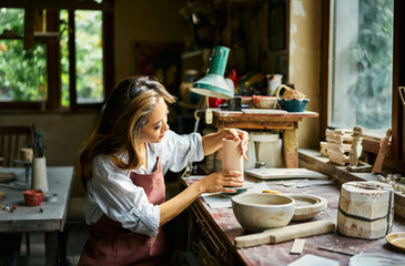Female artist sculpts crafts with ceramic clay at her creative workshop