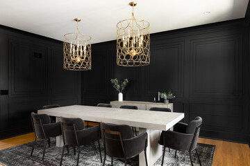 A cozy dining room with a gold chandelier above a wooden table and black wainscoting walls.