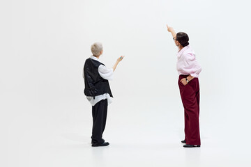 People pointing forward as if discussing or showing something important, collaborating in creative, relaxed environment against white studio background. Concept of DEI, business, partnership.