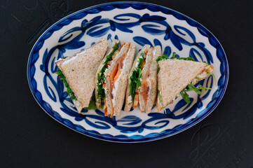 Three delicious smoked salmon sandwiches are artfully arranged on a plate.