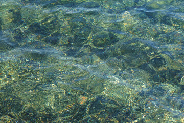 Clear water ripples over smooth rocks on a sunny day