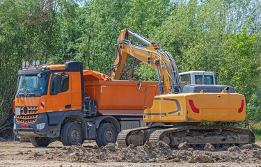 Excavator Digger Loading Dirt in Tipper Truck at Construction Site