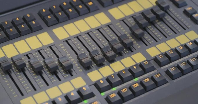 Sound engineer's console working, music studio equipment. Stage lighting, strobe flashes. Real time close up handheld interior shot. Looping 4K video clip.