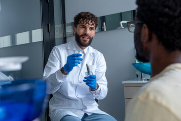 Young man dentist providing consultation in dental office for unrecognizable patient