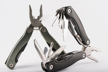 Steel multitool  on white background. Opened multitool with pliers, file, blade, screwdriver, bottle opener and saw, with a white background. Multi tool with expanded tools and pliers