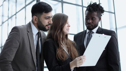 Portrait of three people in business wear discussing document in office.
