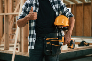Job is going fine, showing thumb up. Industrial worker in wooden warehouse