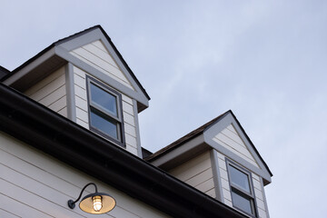 A house with a slanted roof and a window on the top. garret house with roof shingle in evening. © Rattanachat