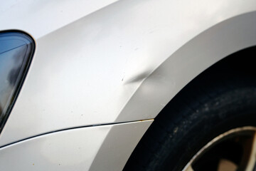 Scratches and dents on car arch, damaged paint surface after side impact, minor collision or accident. Common cosmetic issues that affect the vehicle's appearanceю Selective focus