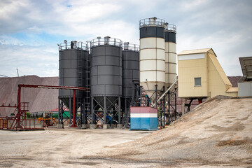 Obraz premium Industrial concrete plant with cement bins and batchers in operation during daytime under a cloudy sky
