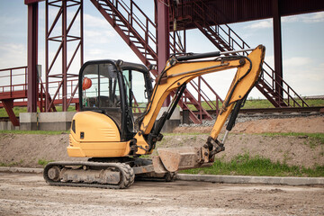 Mini excavator operating at an industrial plant while preparing the site for construction activities in broad daylight © Anoo