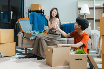 Successful young couple is moving to a nice new place, around boxes with their belongings. The room is very bright and bright, they are wearing casual clothes.