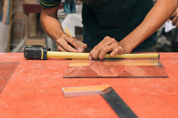 A person measures a piece of glass with a ruler