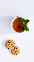 cup tea two cookies on a white surface