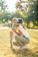 Fototapeta premium Young mother and little daughter hugging and playing together in autumn park in Prague, Europe