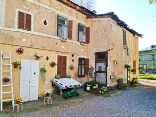 Fototapeta premium Old house yard decor on a sunny fall day. wooden door, stairs, potted flowers, pumpkin decorate the yard and create coziness.