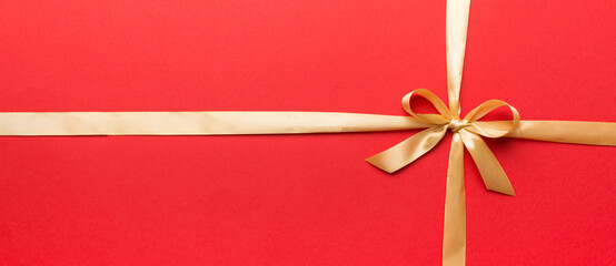 Top view of gold ribbon rolled and yellow bow isolated on colored background. Flat lay with copy...