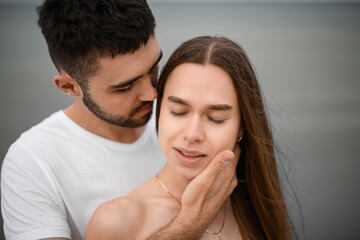 Close-up of the faces of a man and a woman in love. A man stands behind a woman and caresses her face with his hand