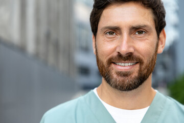 Smiling bearded man doctor in uniform standing outdoor medical center