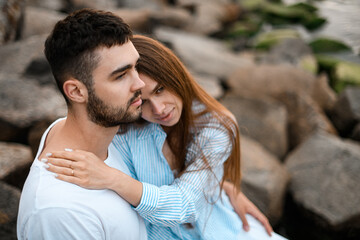Fototapeta premium Young woman sits on the arms of her husband, putting her hands on his shoulders