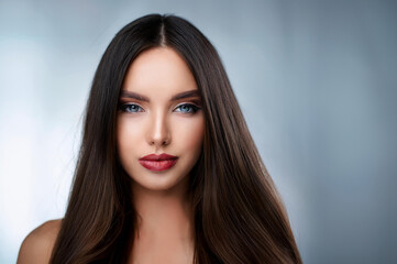 Fototapeta premium Junge Frau mit langen glatten Haaren vor neutralen Hintergrund