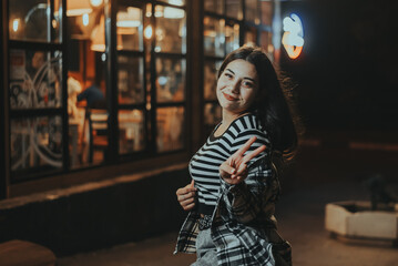 Happy Brunette Posing Near a Cafe at Night