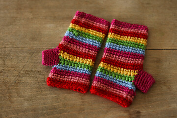 Colorful crochet gloves on a wooden background. Handmade.