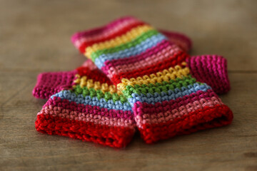Colorful crochet gloves on a wooden background. Handmade.