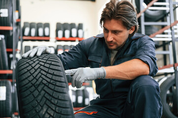 Warehouse with many tires. Man is in the tire fitting car service