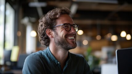 Side view portrait of a smiling Caucasian man working at a computer in an office workplace, minimal background focusing on his expression.