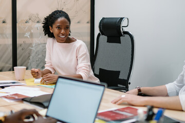 Successful multicultural male and female finance professionals coworking together near office desktop discussing details for management startup project, concept of entrepreneurship and teamwork