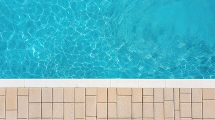 Obraz premium Top view of a swimming pool with clear blue water and sun reflections next to a tiled pool deck.