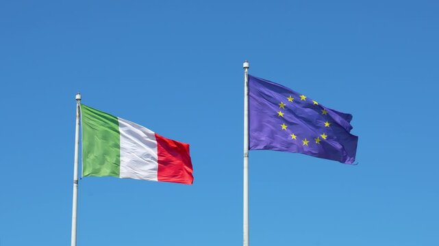 The flag of Italy and the flag of the European Union against the blue sky