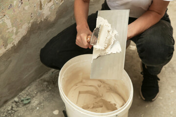 Woman plastering wall with putty-knife. Fixing wall surface and preparation for painting. DIY housing improvement project.