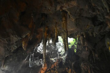 stalagmites and stalactites with sunlight through cave hole in Khao Luang cave travel location on Thailand