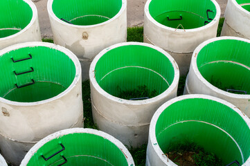 Precast concrete pipes made of cement are stacked on the ground in an industrial plant. Concrete circle pit  on construction site. Installing Concrete Rings Risers for Sewer Well for Wastewater. 