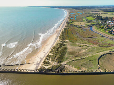 Aerial view of a Suffolk coasting beach. The bottom of the image shows an abandoned concrete pier which leads into a salt water river.