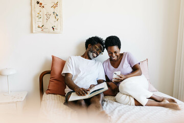 Couple relaxing in bed enjoying leisure time together with books and technology