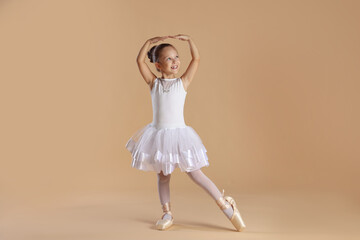 Naklejka premium Little ballerina practicing dance moves on beige background