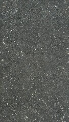 Textured black asphalt surface with white specks in bright daylight setting
