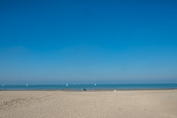A tranquil beach scene that beautifully showcases golden sands, gentle waves, and a bright blue sky overhead