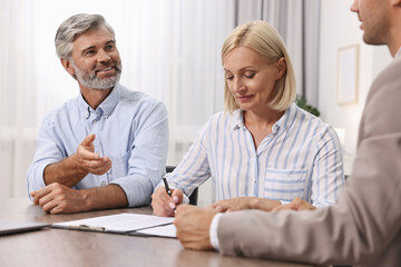 Obraz premium Pension plan. Couple consulting with insurance agent at table indoors