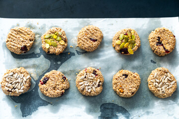 Homemade crispy oatmeal cookies with pumpkin and sunflower seeds on parchment paper. A healthy snack, perfect for a morning energy boost.