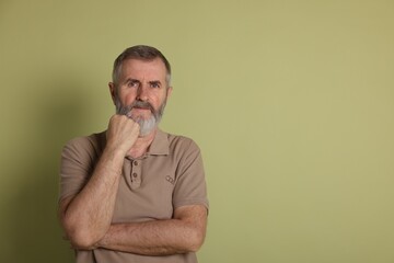 Portrait of senior man on green background, space for text